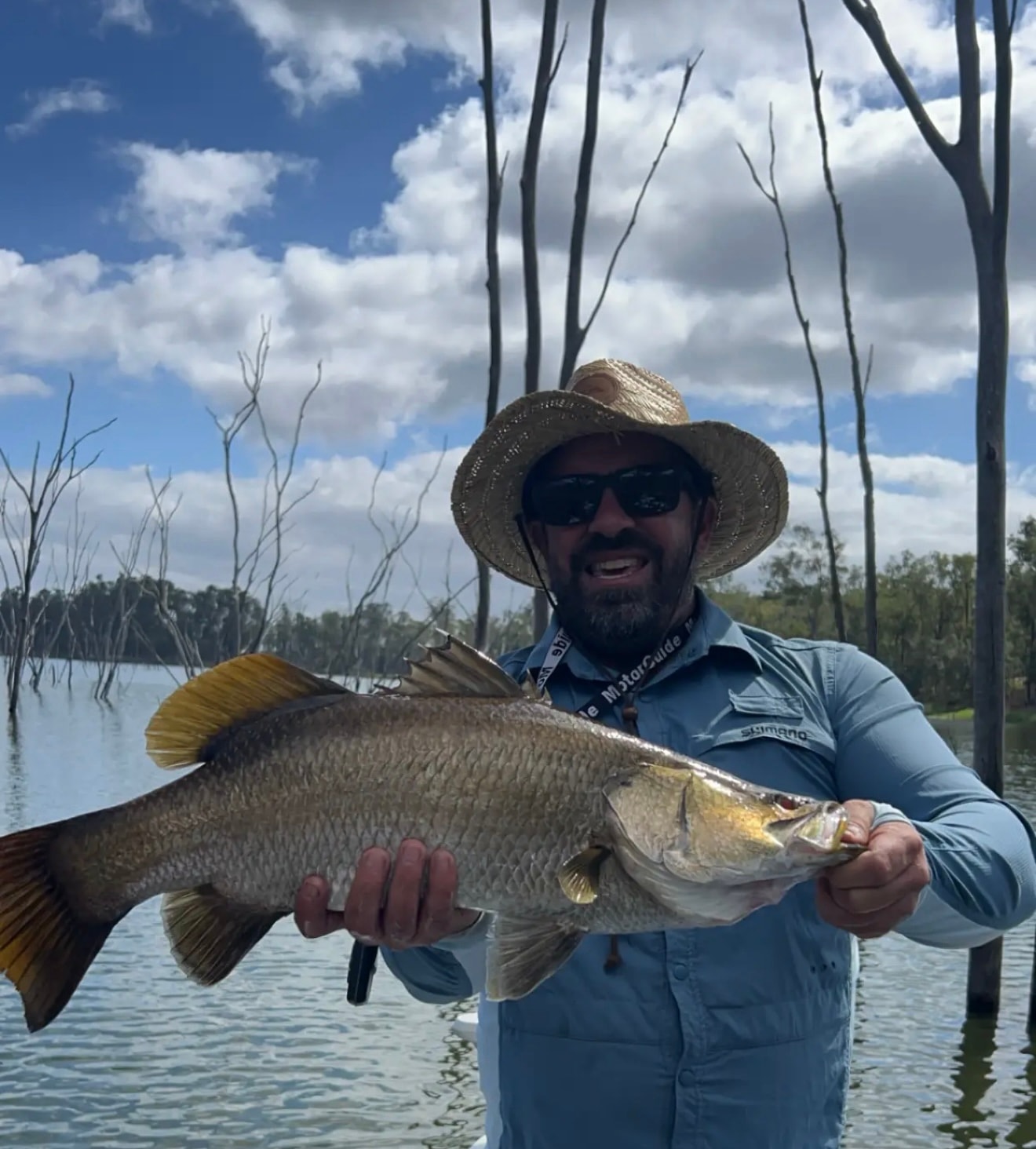 Ben, co-founder of Cutlass, holding a barramundi on the water